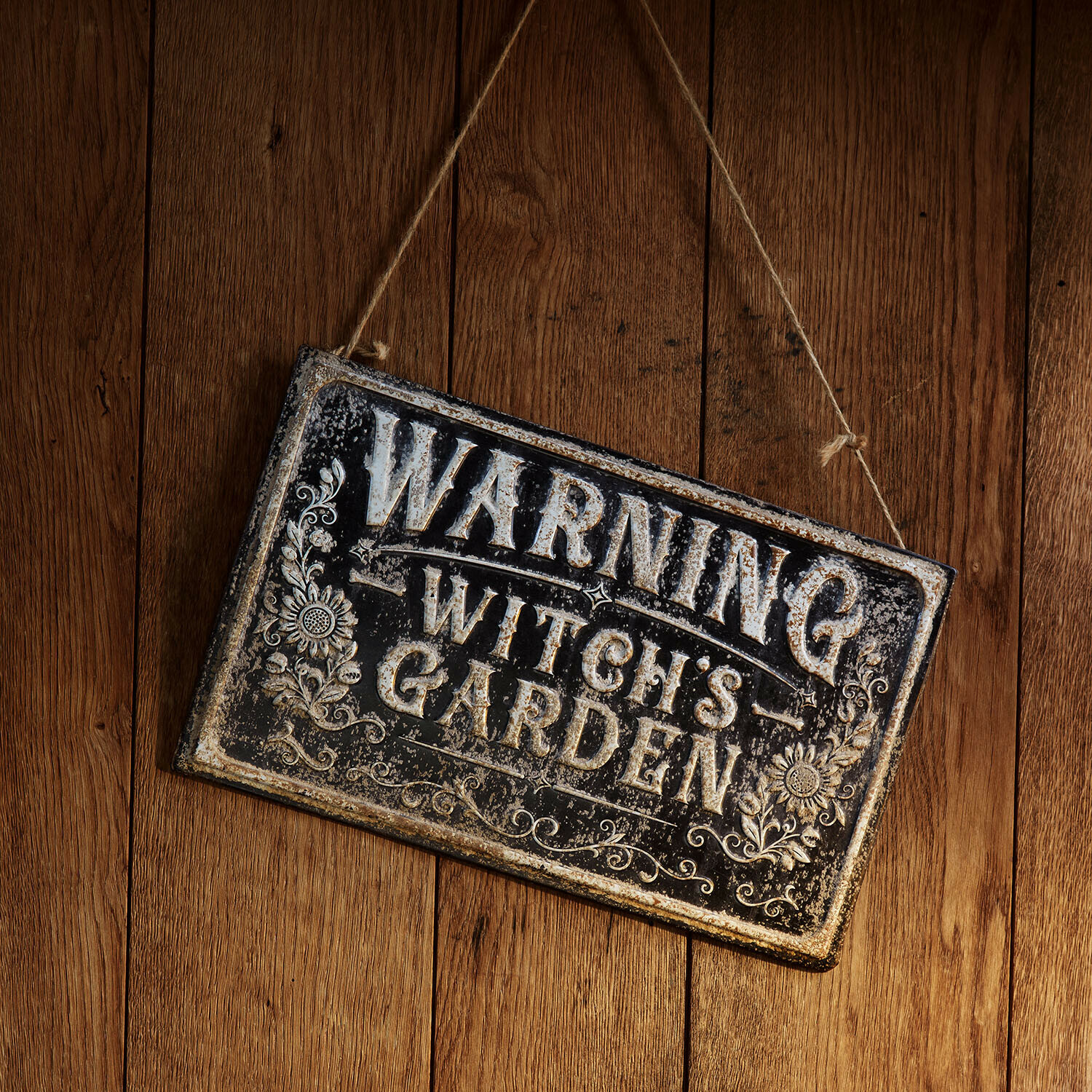 Metalen vintage waarschuwingsbord met tekst Witch's Garden aan houten achtergrond