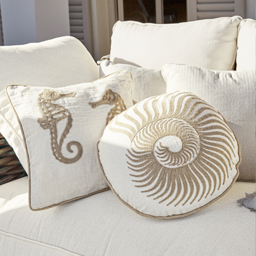 Decoratieve kussens met zee-motieven op crèmekleurige stof op bank, maritieme stijl