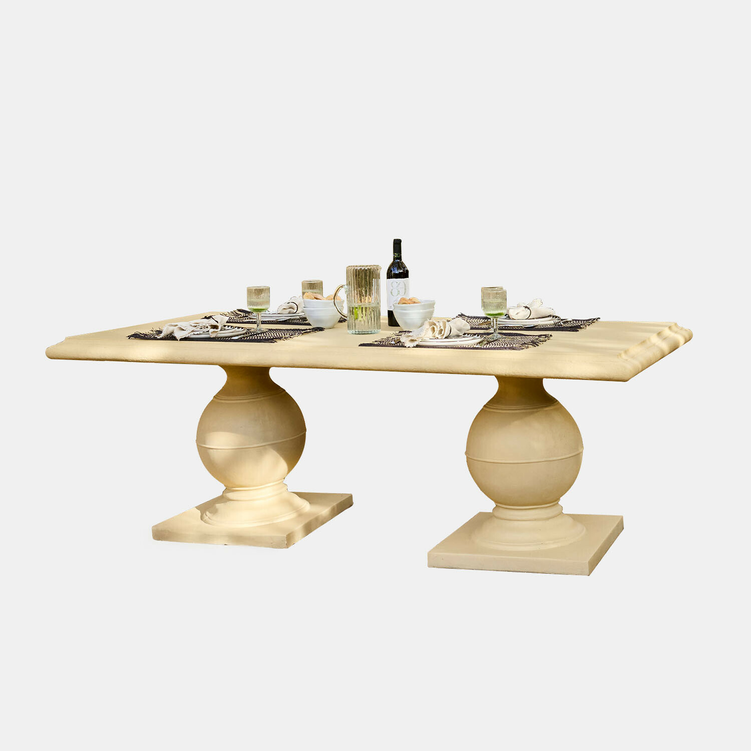 Grande table à manger en pierre beige avec deux pieds sphériques et vaisselle posée dessus