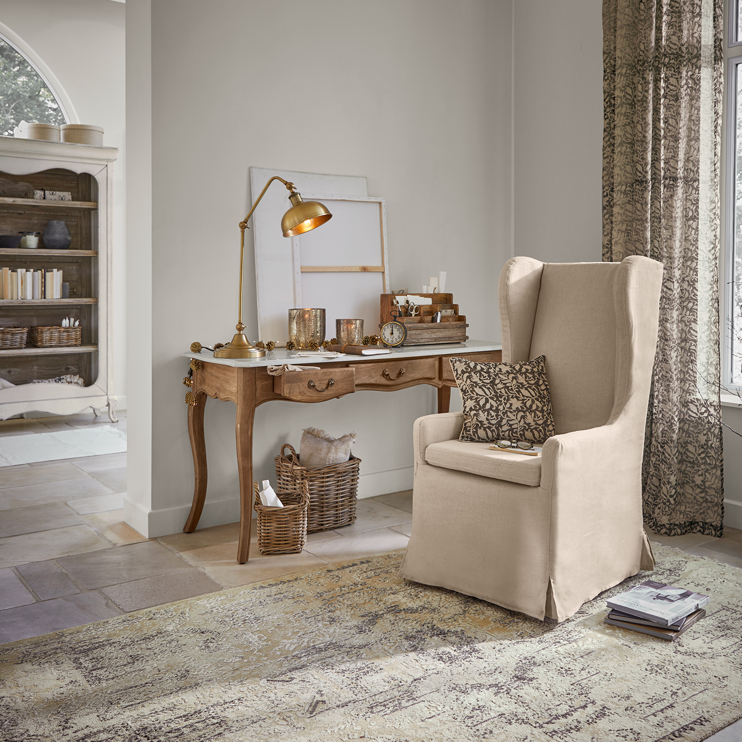Fauteuil beige en tissu style oreiller dans un salon classique avec bureau en bois et lampe de table