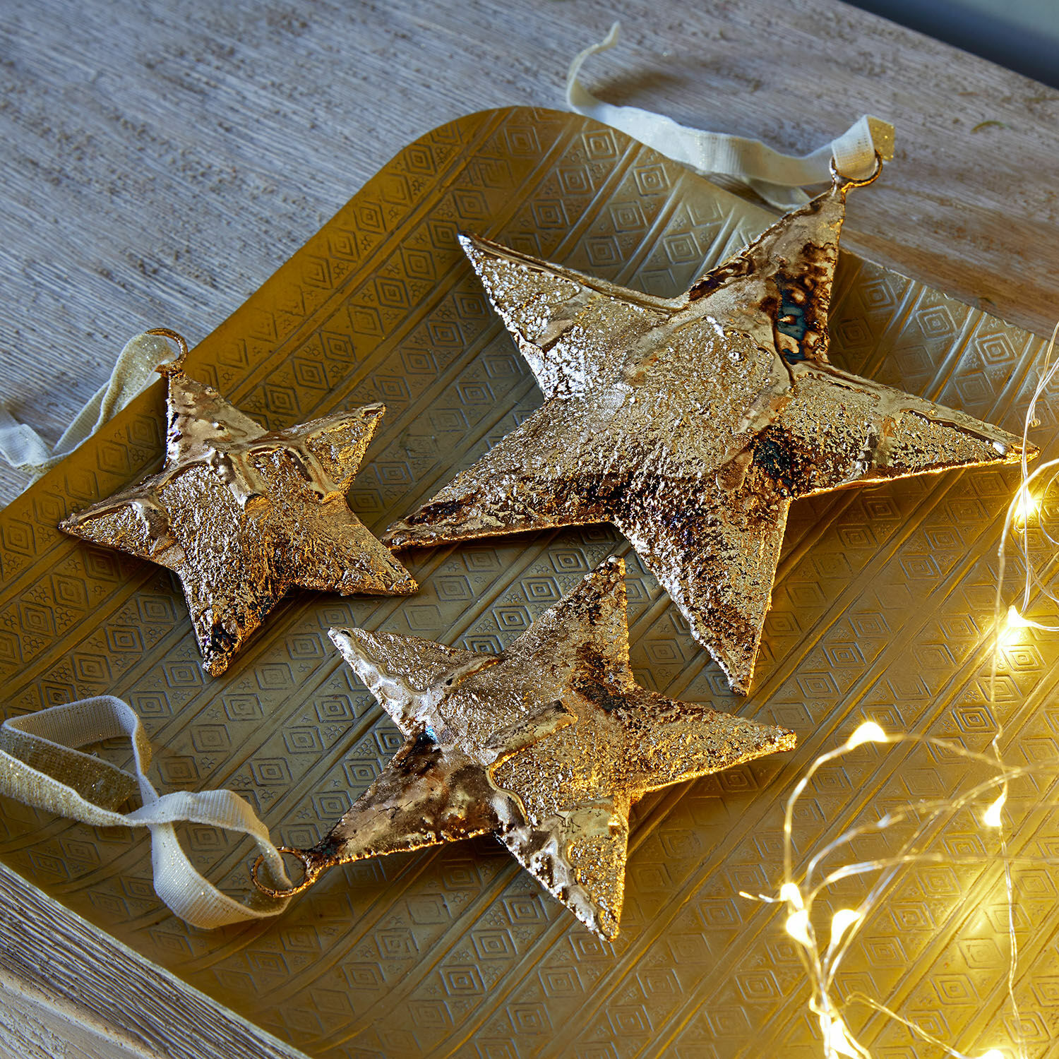 Hanger set van 3 Myrska Set van drie gouden metalen sterren als decoratie op een gouden dienblad met LED-lichtjes