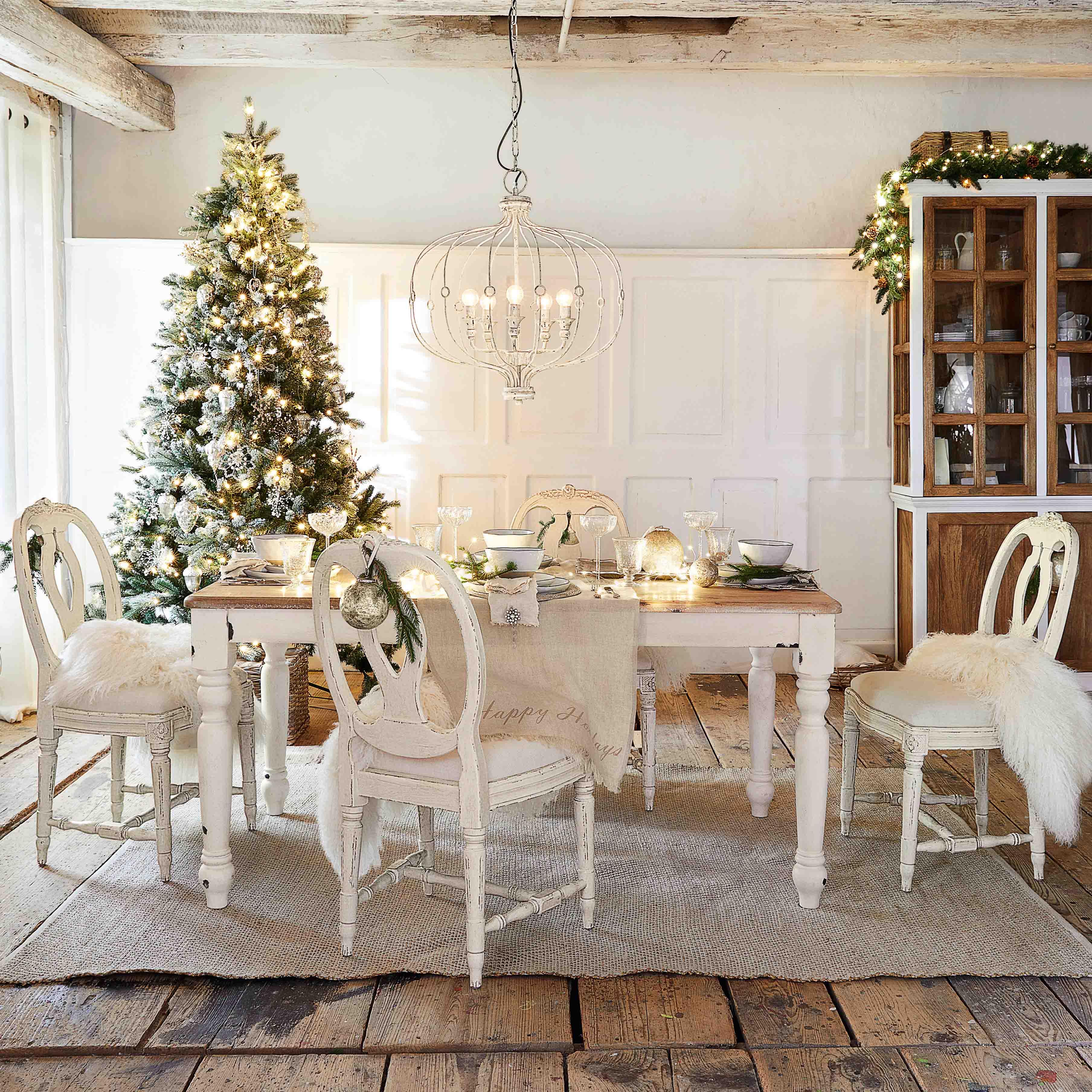 Rustieke eetkamer met witte houten tafel en stoelen, kerstversiering met verlichte boom en hanglamp