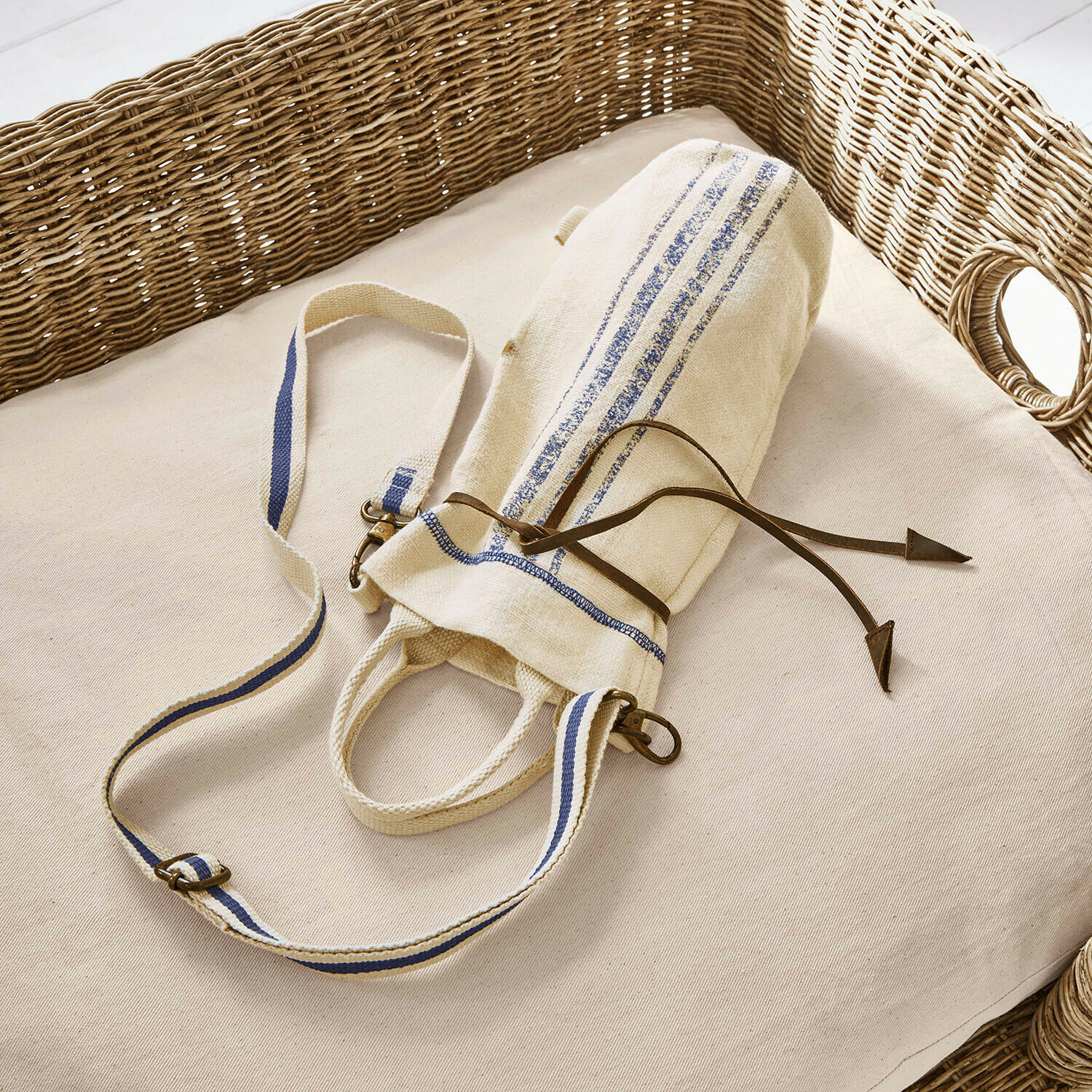 Sac pour bouteille Pawera Sac en coton beige avec bandes bleues et cordon en cuir sur coussin clair avec dossier en osier
