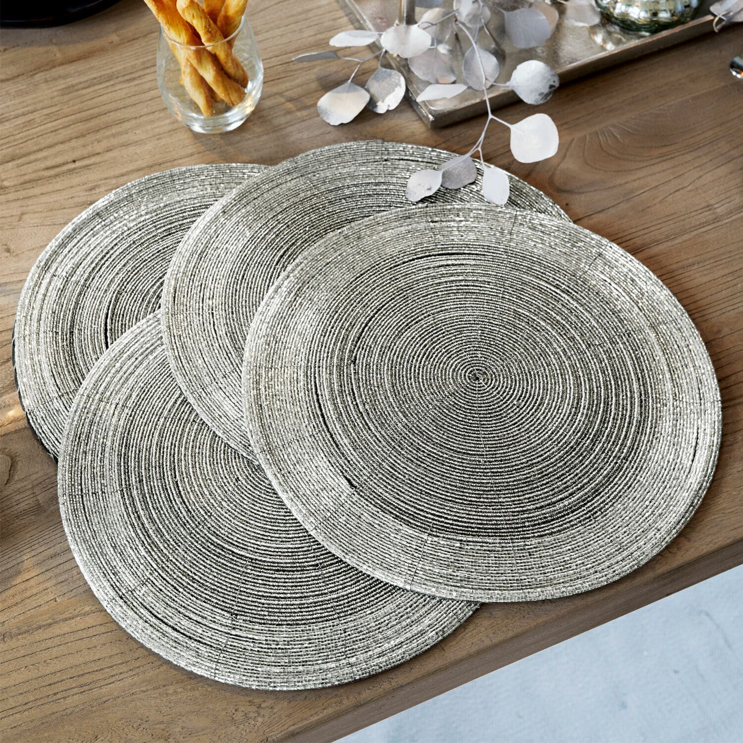 Placemat set van 4 Barningham Set van vier ronde zilveren placemats met geweven textuur op houten tafel