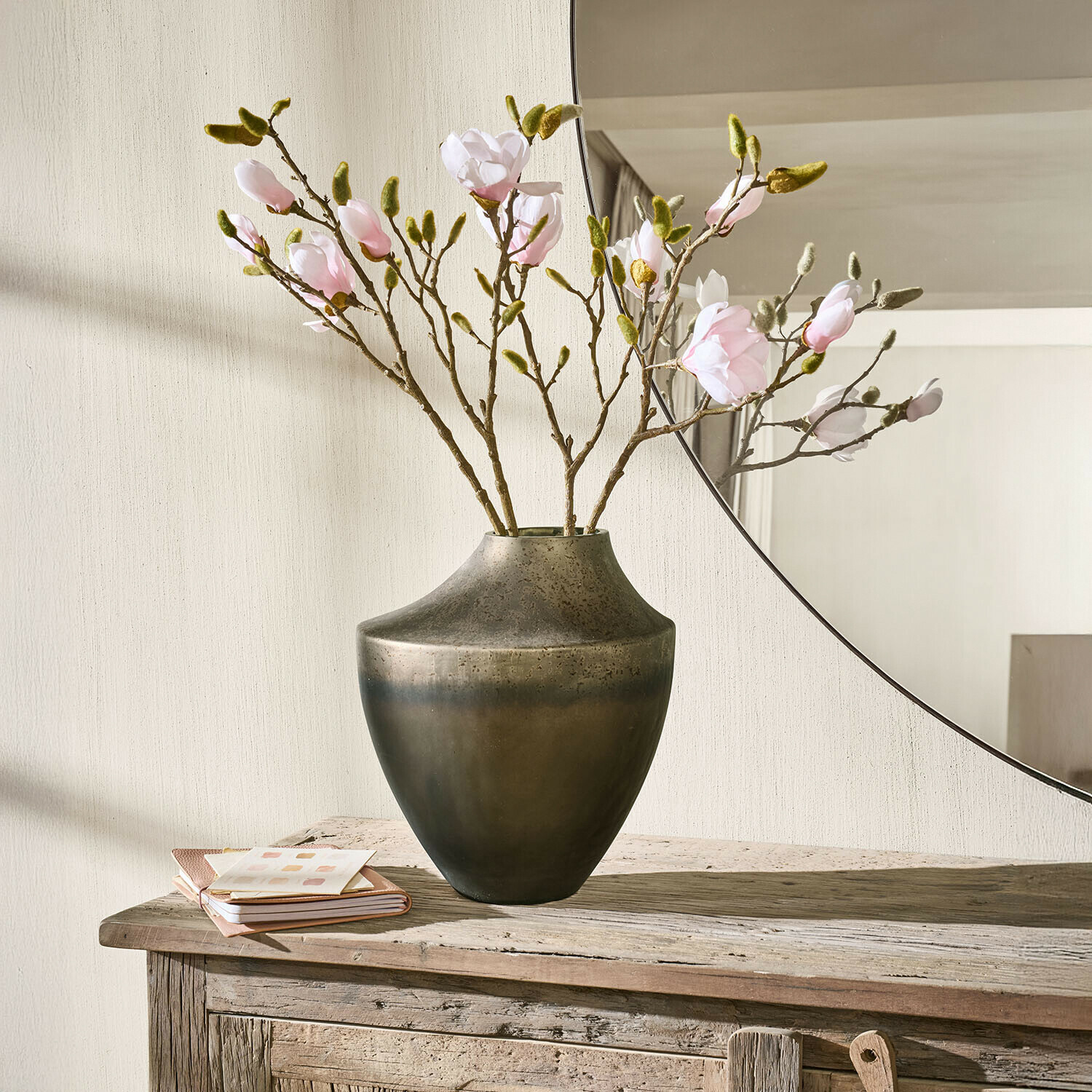 Vaas Tavris Metalen vaas in donkerbruine kleur met takken roze bloemen op rustieke houten tafel