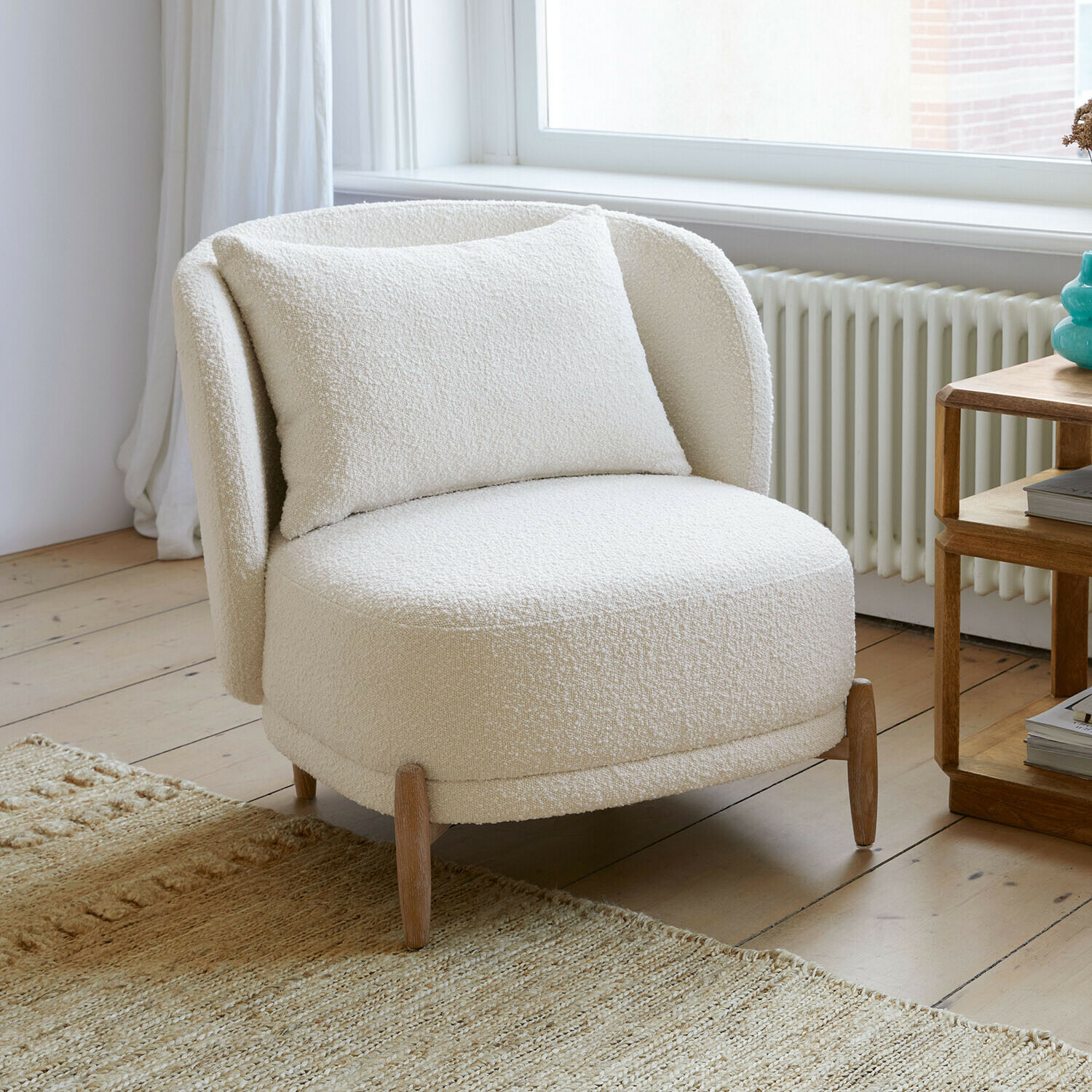Stoel Thamira Witte fauteuil van zachte boucle-stof met houten poten in lichte woonkamer
