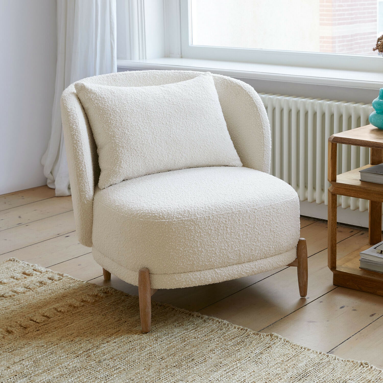 Stoel Thamira Witte fauteuil van zachte boucle-stof met houten poten in lichte woonkamer
