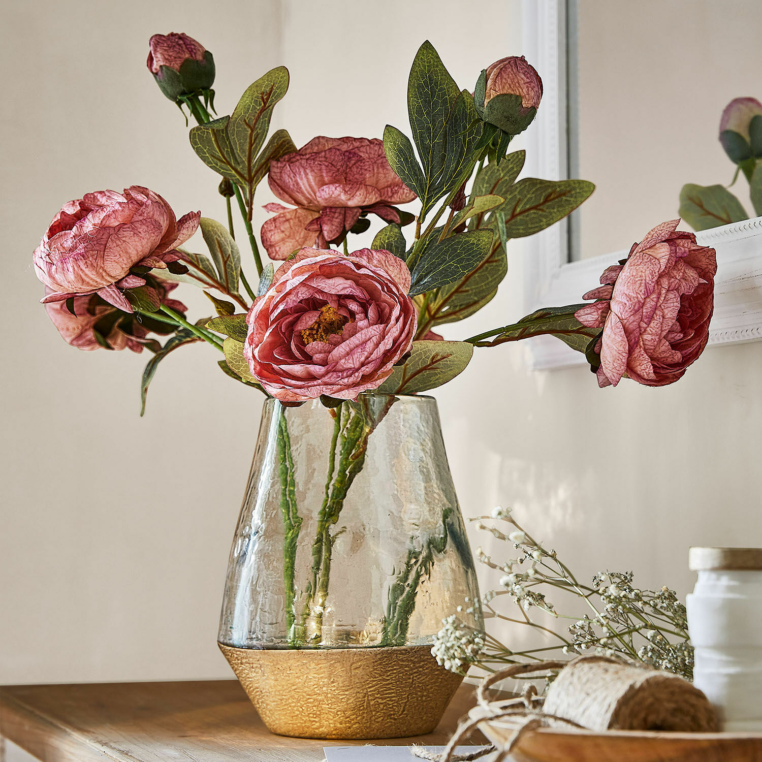 Lot de 3 fleurs décoratives Gilgandra Vase en verre avec base dorée texturée et fleurs roses décoratives sur une table en bois