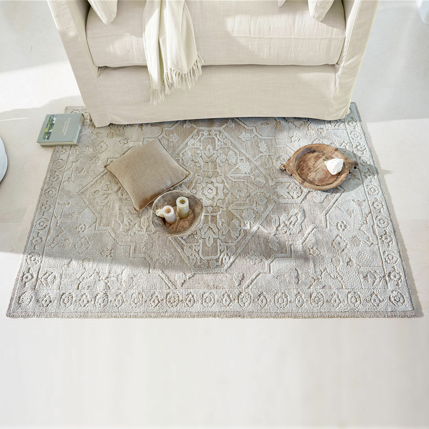 Tapis Armidale Tapis beige à motif délicat sous un canapé clair avec coussin et décorations au sol