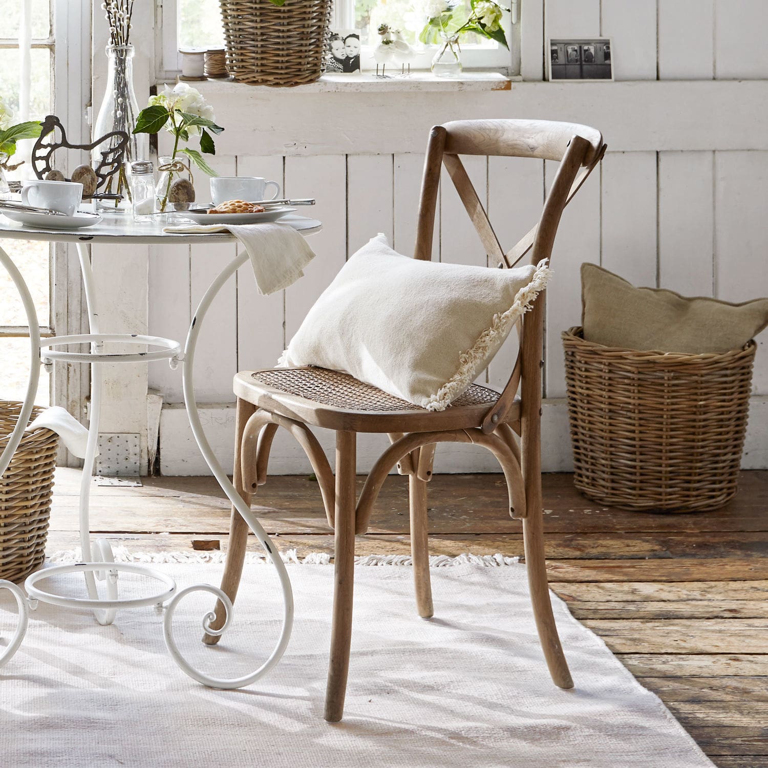 Chaise Kary Chaise en bois avec assise en osier et coussin crème dans un intérieur rustique lumineux