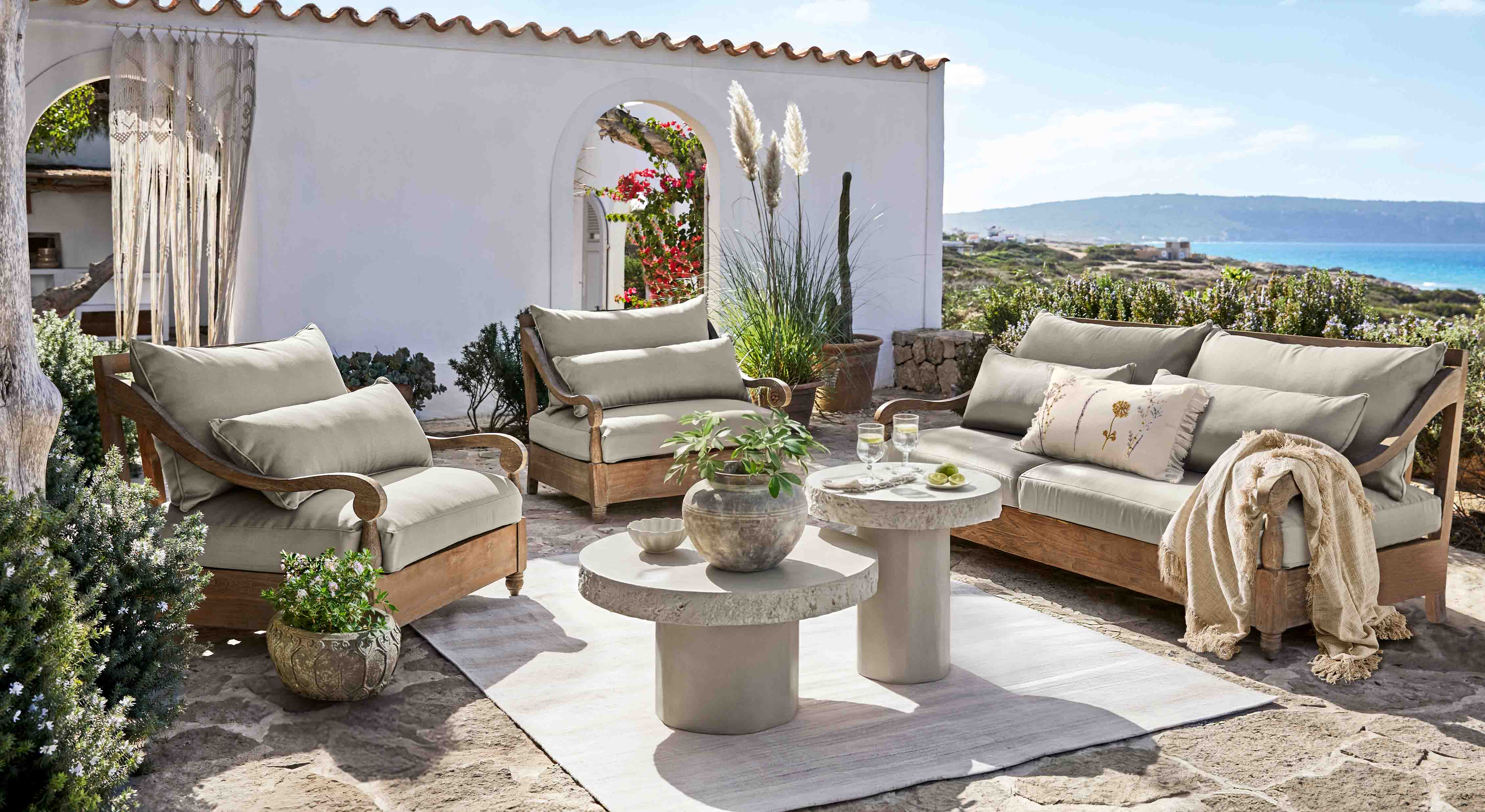 Ensemble de mobilier de jardin en bois avec coussins gris sur terrasse face à la mer