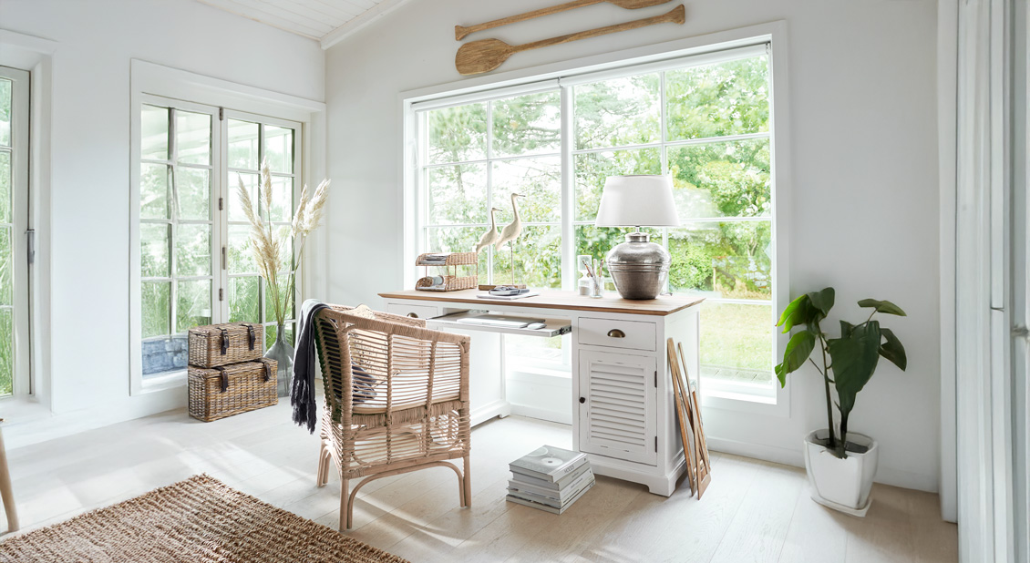 Bureau lumineux avec bureau en bois blanc et chaise en osier dans un style inspiré de la côte