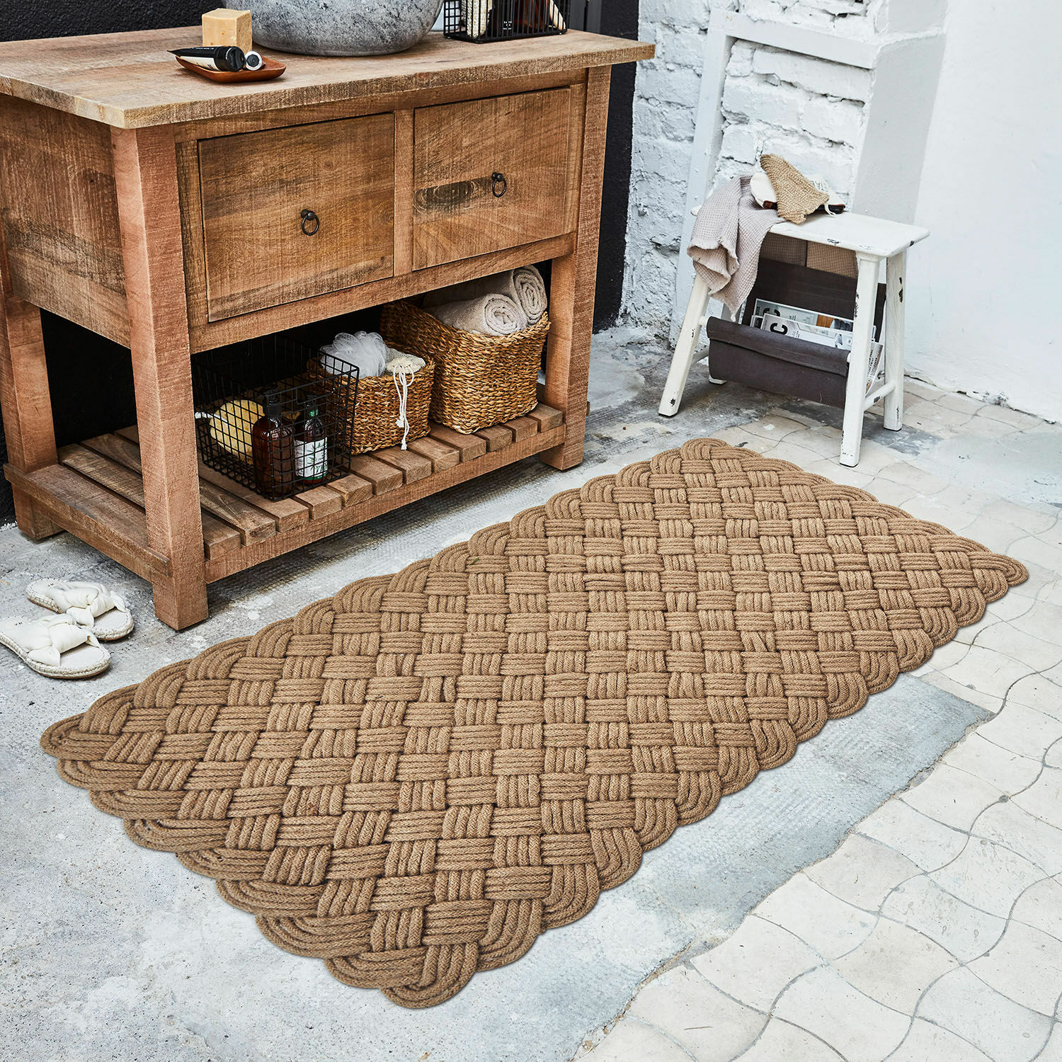 Tapis long Hildas Tapis marron en corde tressée posé au sol près d'une commode en bois et d'un tabouret blanc