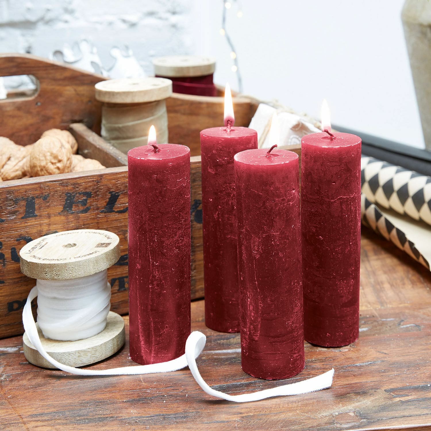 Kaars set van 4 Muriel Vier rode waskaarsen op houten tafel met decoratieve spoelen en walnoten