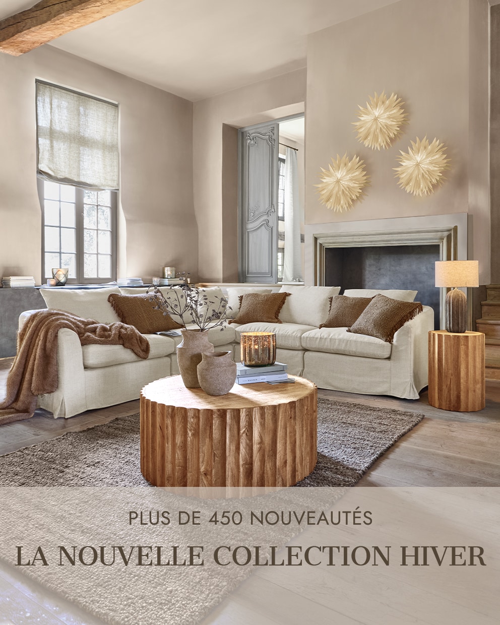 Salon chaleureux avec canapé beige, table basse en bois et décorations murales pour la nouvelle collection hiver