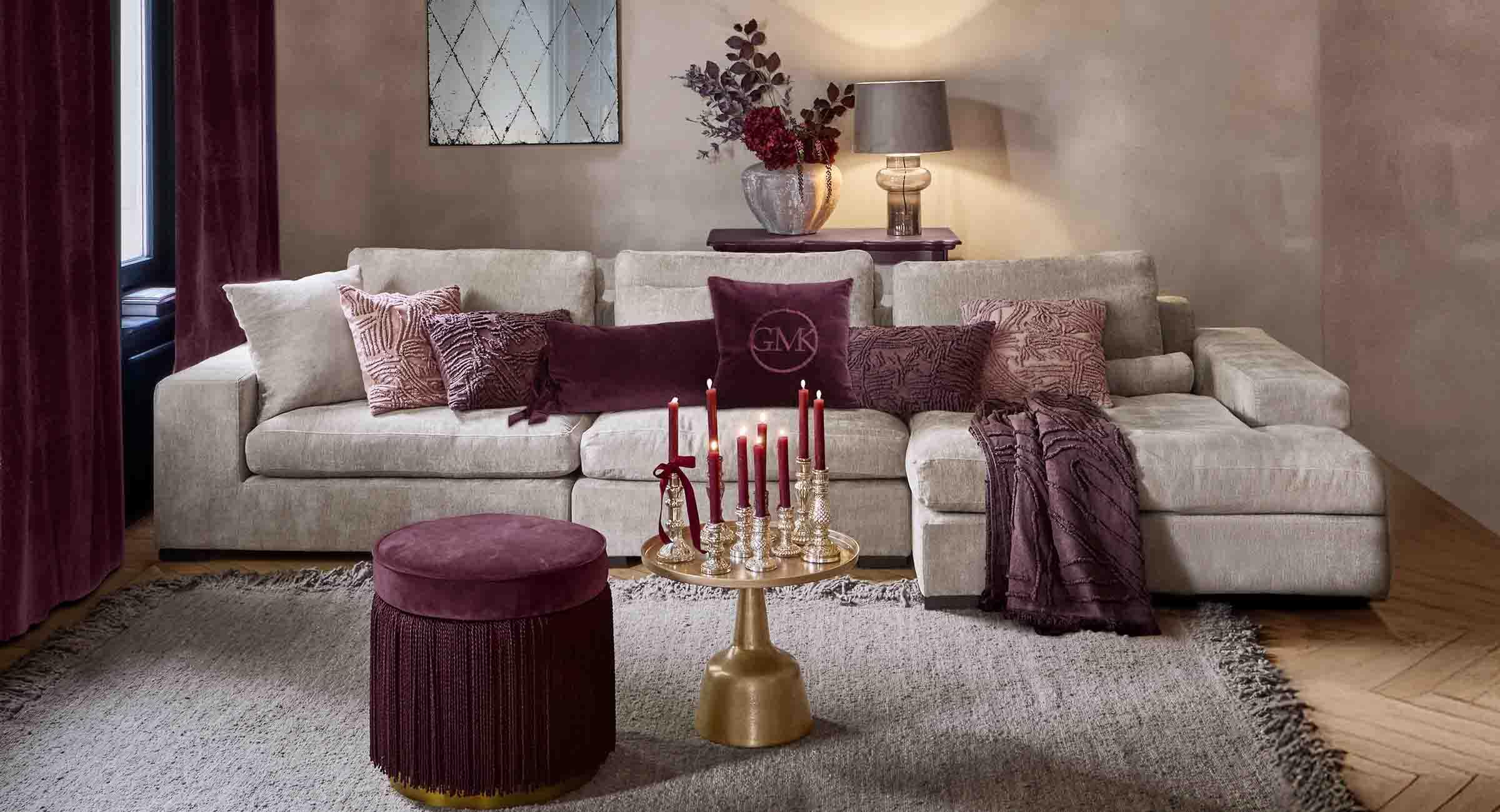 Canapé beige avec coussins doux et accessoires bordeaux dans un salon élégant avec lampe et miroir