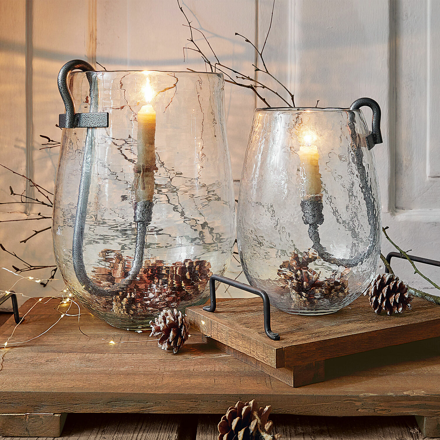 Lot de 2 photophores Lorcalla Deux lanternes en verre transparent avec poignées en métal et bougies, décorées de pommes de pin