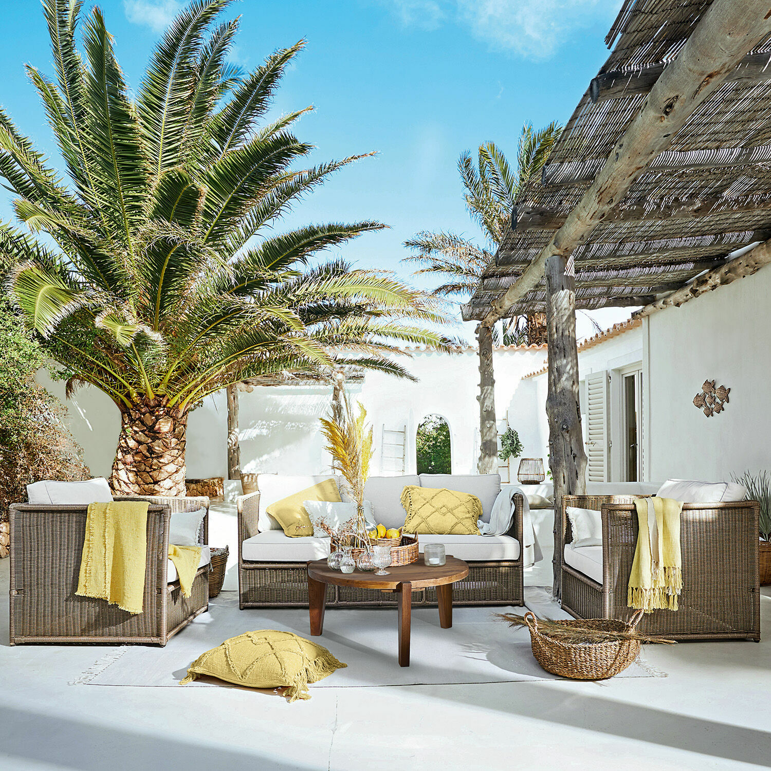 Salon de jardin Lesmont Ensemble de mobilier de jardin en rotin brun avec coussins crème et accents jaunes sur terrasse ensoleillée