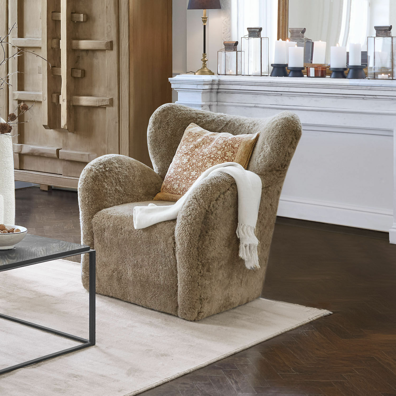 Fauteuil Ambrécourt Fauteuil beige en tissu doux avec coussin et plaid blanc dans un salon élégant