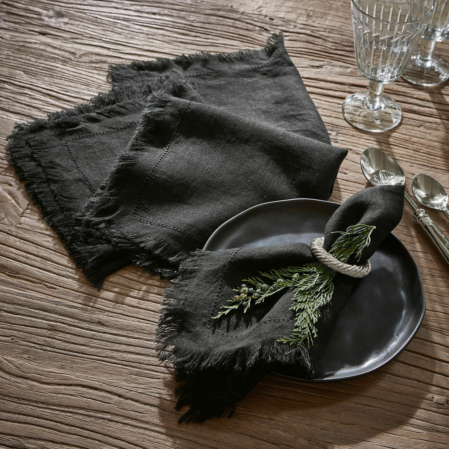 Lot de 4 serviettes de table Pibrac Serviettes en lin noires à franges sur table en bois avec décoration de branches vertes