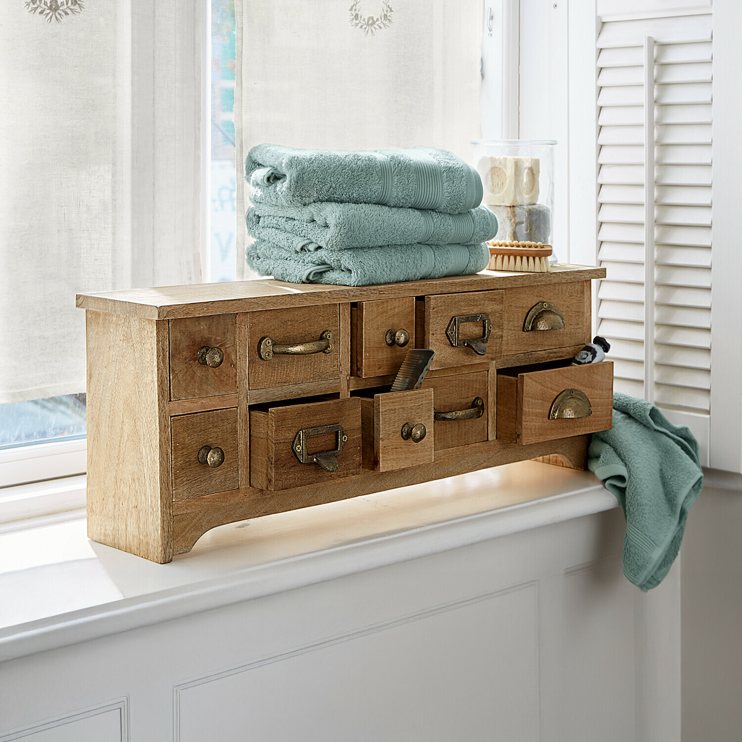 Organiseur Lhomme Meuble en bois avec plusieurs tiroirs et serviettes vertes douces posées sur un rebord de fenêtre