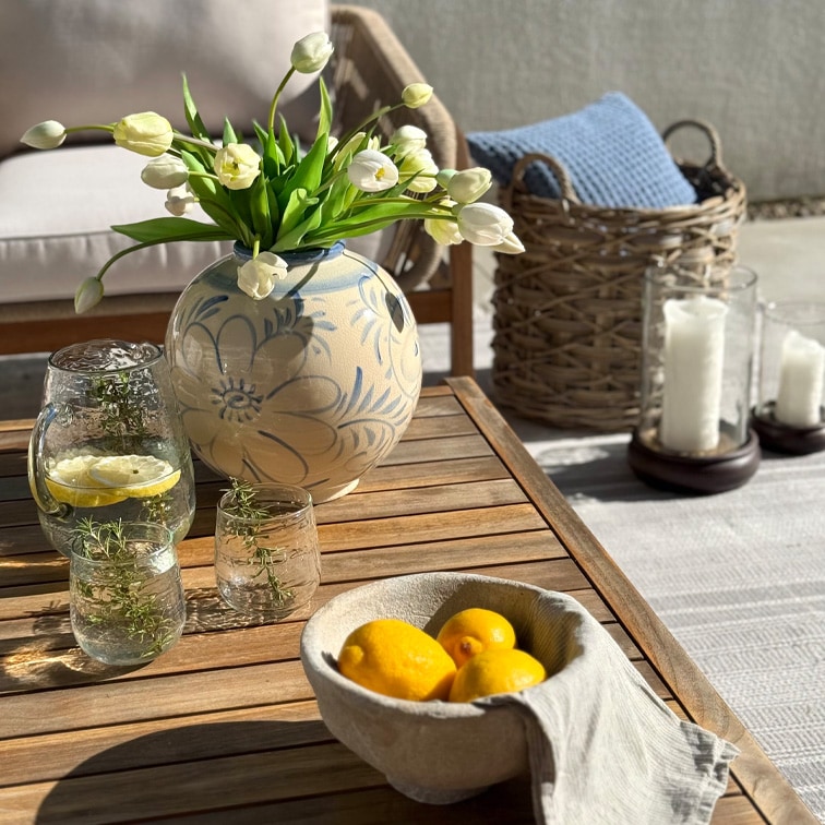 Decoratieve keramische vaas met bloemenpatroon en witte tulpen op houten tafel op terras