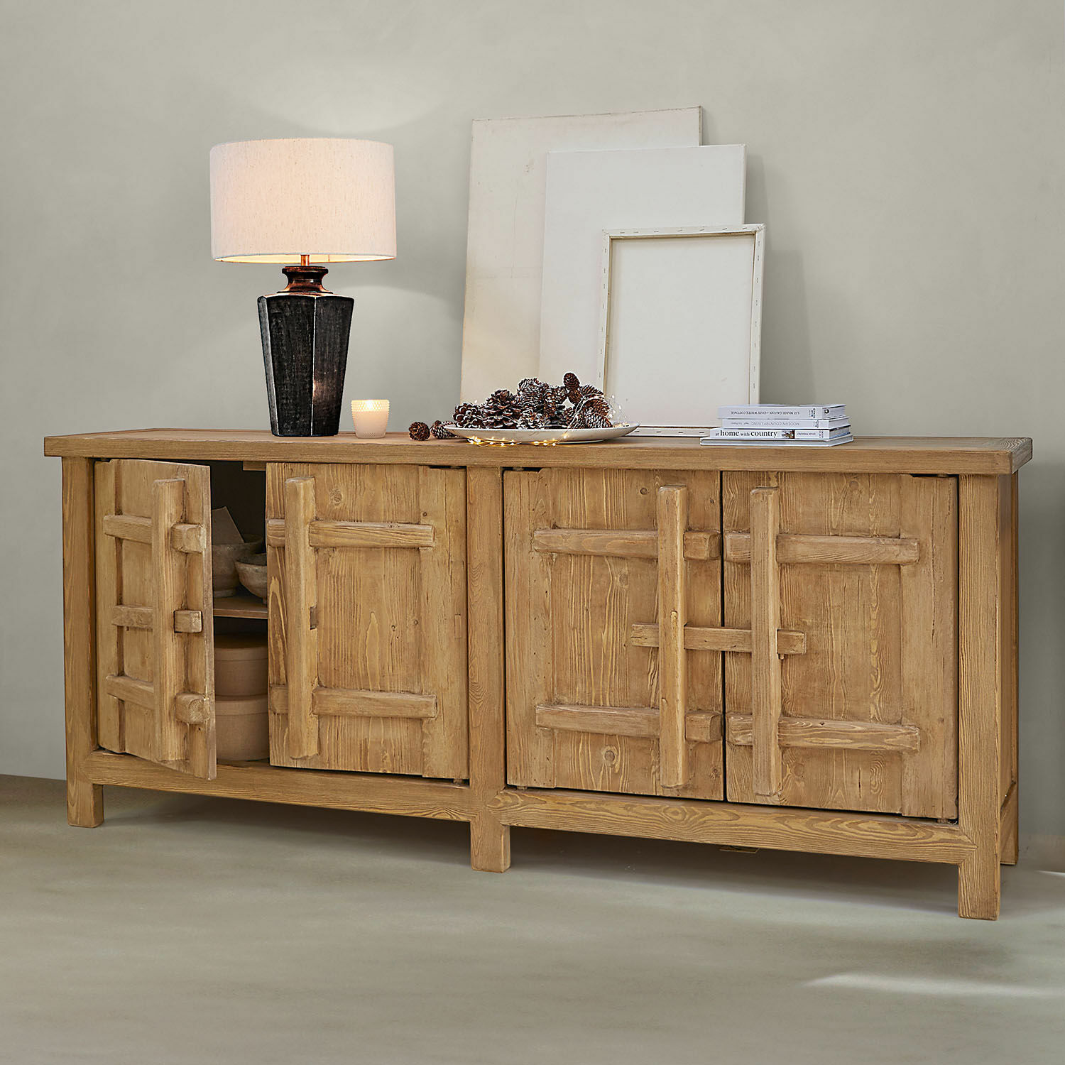 Buffet en bois naturel avec quatre portes, lampe et décorations sur le dessus dans un intérieur moderne