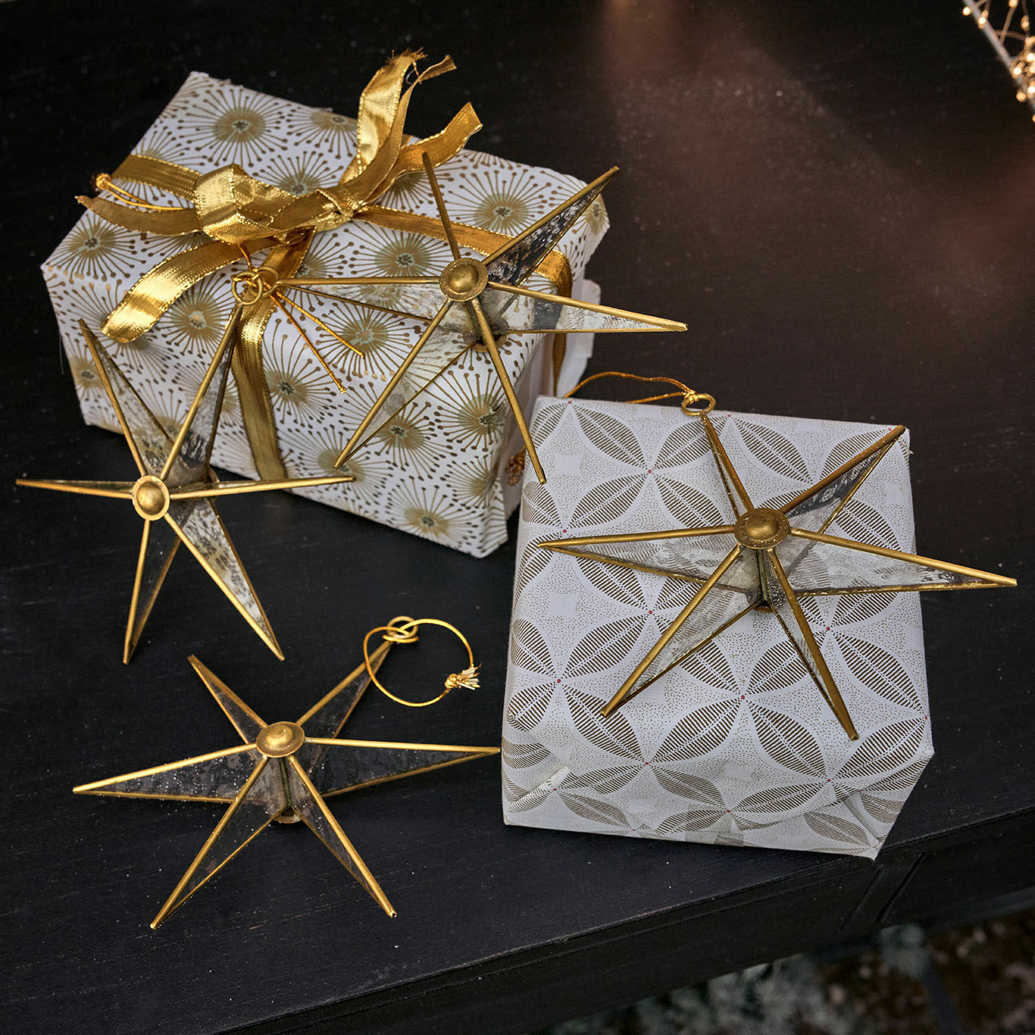 Lot de 4 décorations à suspendre Zaydan Étoiles décoratives en métal doré sur des cadeaux emballés avec papier blanc et ruban doré