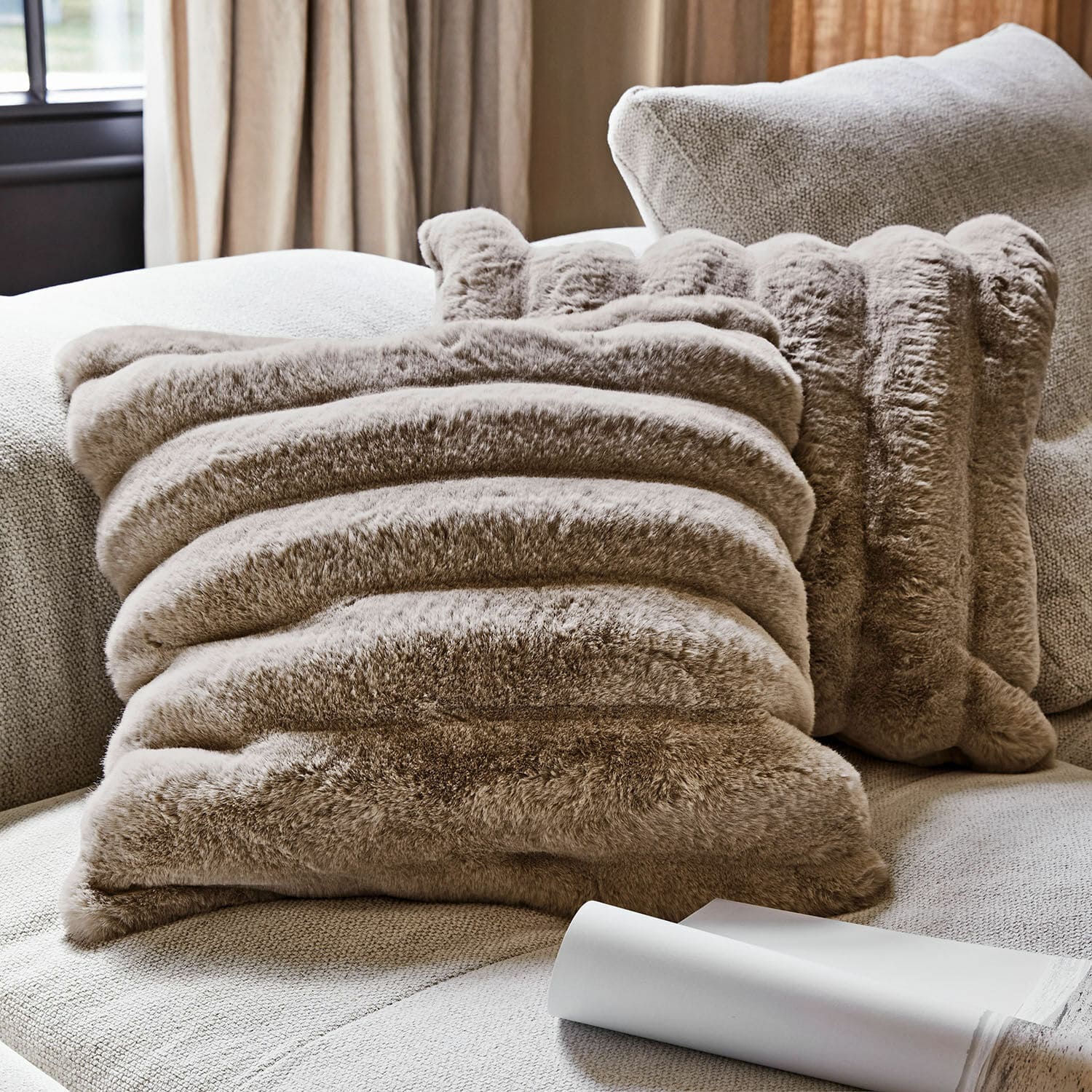 Lot de 2 housses de coussins Caelira Coussin décoratif en fausse fourrure beige sur canapé clair pour salon cosy