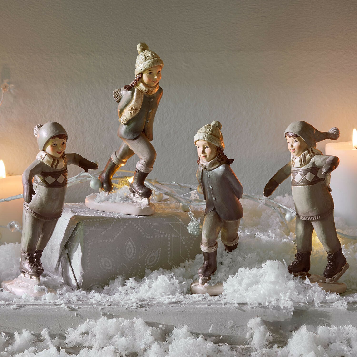 Lot de 4 figurines Mériot Figurines d'enfants en céramique patinant en beige et gris sur une table décorée de neige artificielle