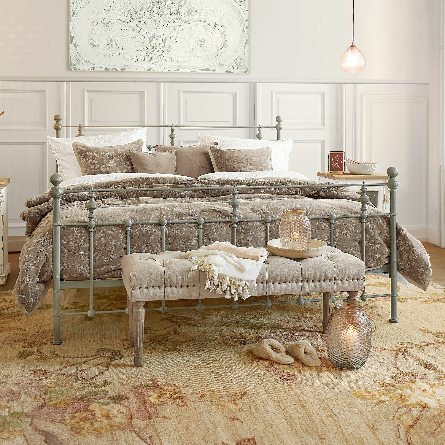 Bed Beauvierre Slaapkamer met grijs metalen bed, beige beddengoed met bloemmotief en zachte gestoffeerde bank aan het voeteneinde