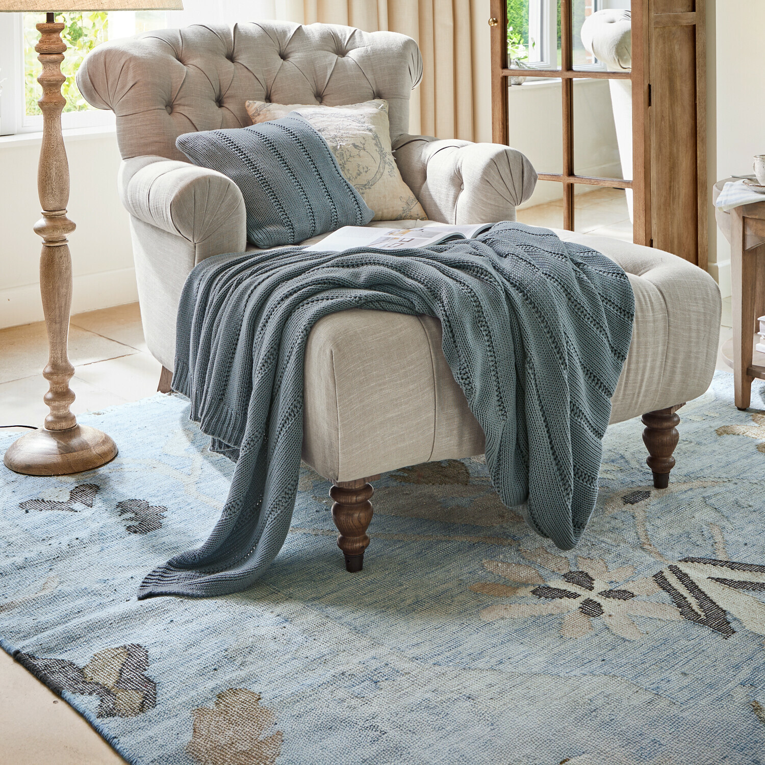 Plaid Lémeré Beige stoffen fauteuil met gestikte rugleuning en blauwe gebreide deken in woonkamer