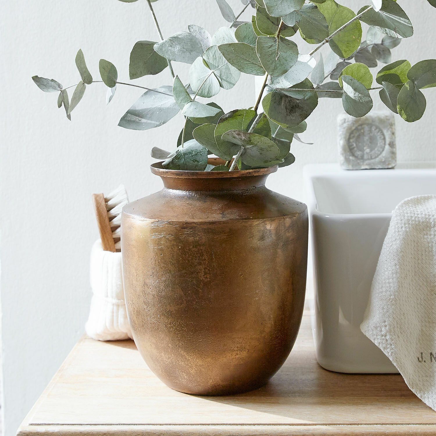 Vaas Toulane Messing vaas met groene eucalyptusbladeren op houten tafel in lichte kamer