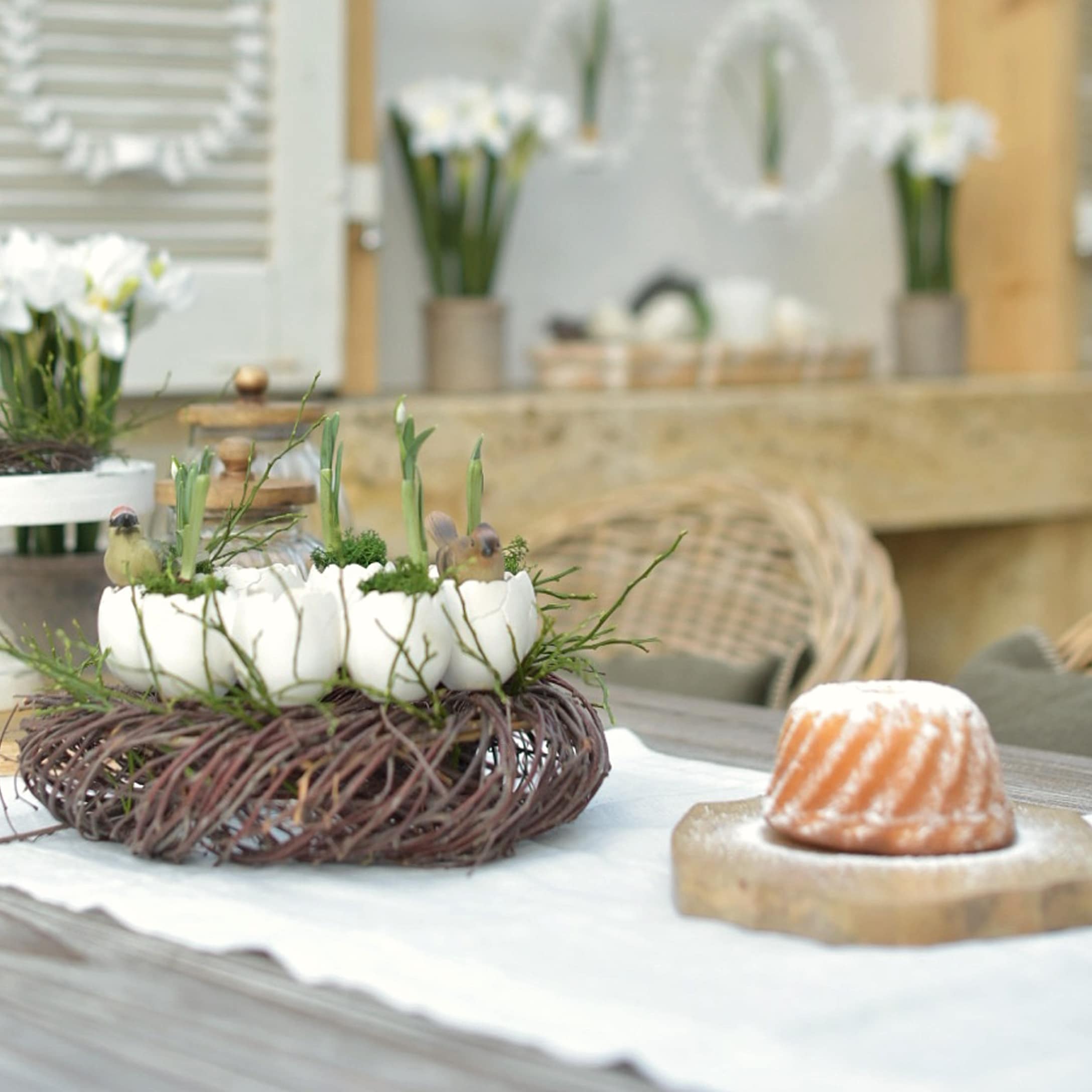 Couronne décorative en branches naturelles avec pots en céramique blanche et plantes vertes sur table