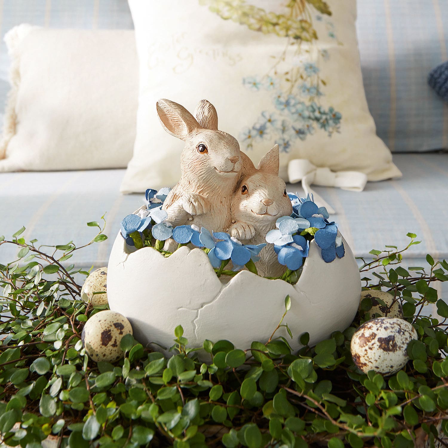 Hazen met ei Miksa Decoratie met twee konijnen in een witte eierschaal, blauwe bloemen en groen blad