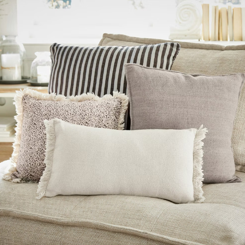Ensemble de quatre coussins décoratifs aux tons neutres sur un canapé beige, textiles pour salon