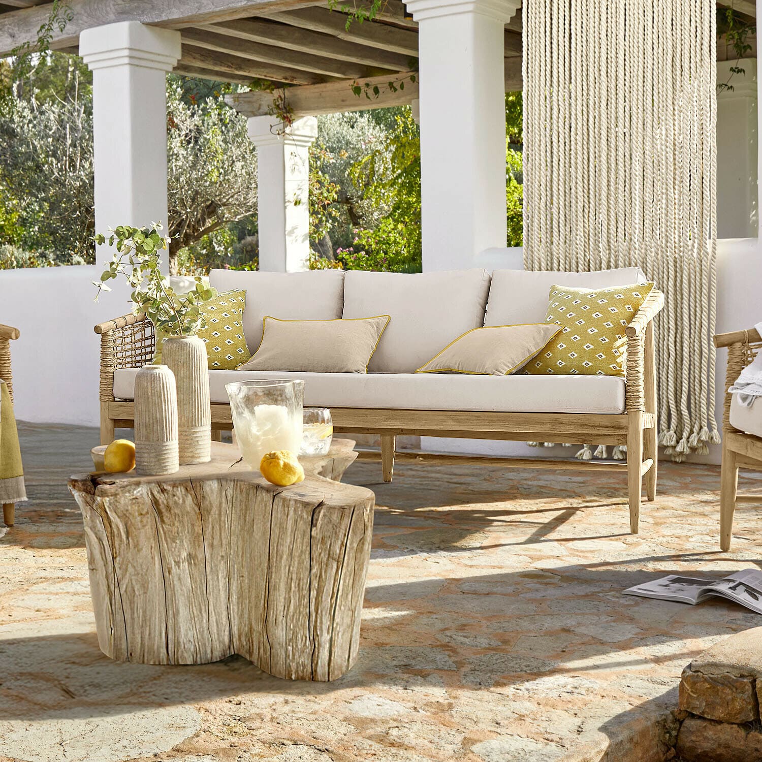 Bank Roselva Licht houten bank met beige kussens en gele accenten op terras met stenen vloer