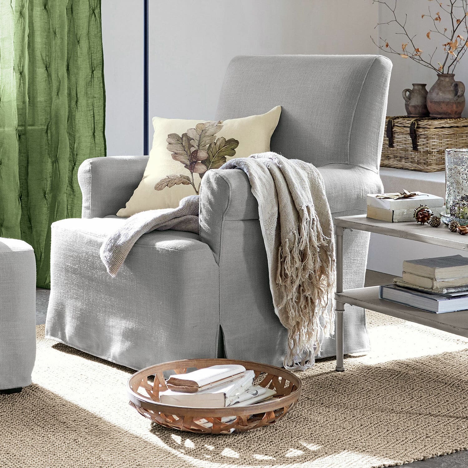 Fauteuil Nasour Fauteuil gris en tissu avec coussin décoratif et plaid beige dans un salon chaleureux