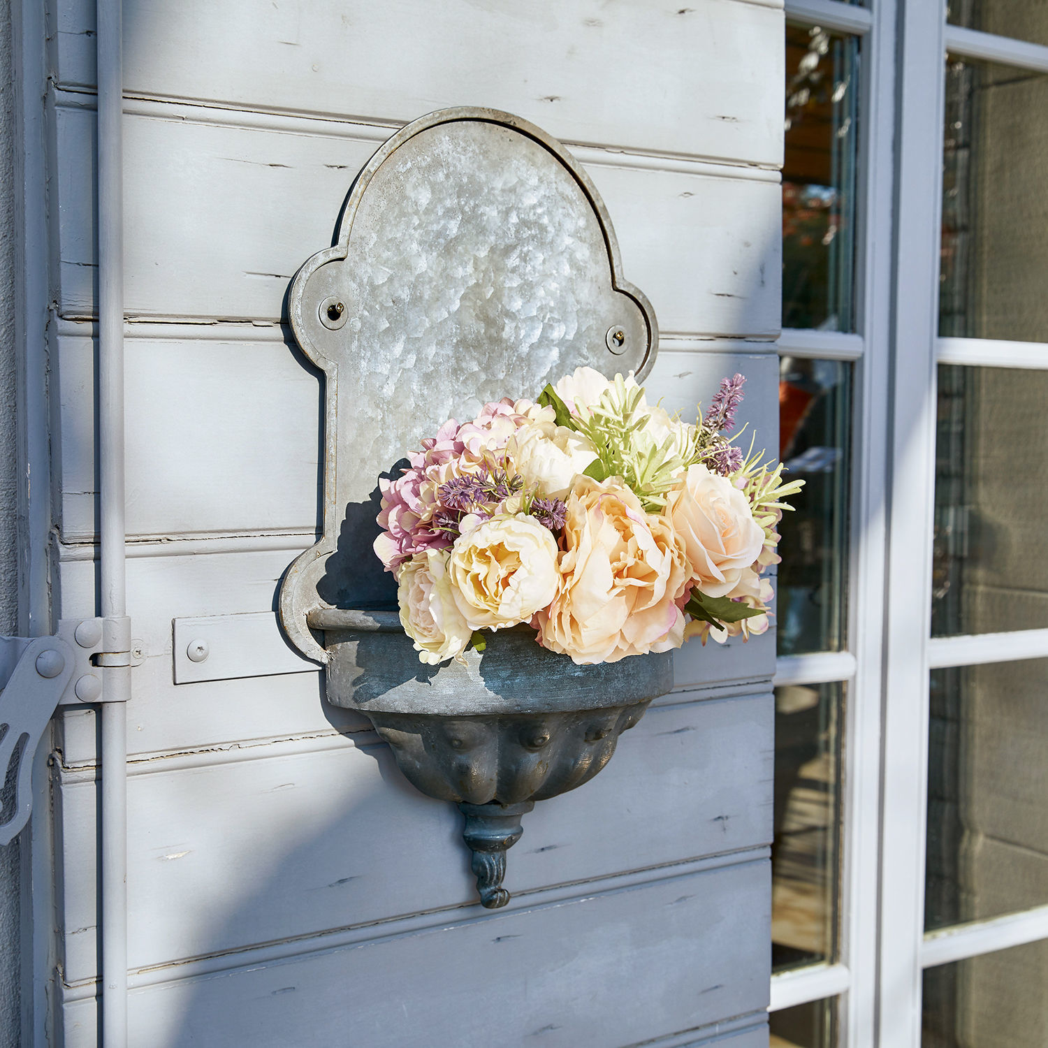 Pot de fleurs fontaine Millieur Jardinière murale en métal avec fleurs pastel fixée sur un mur gris clair extérieur