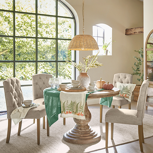 Salle à manger avec table en bois et chaises beige rembourrées, décorations naturelles et lumière naturelle