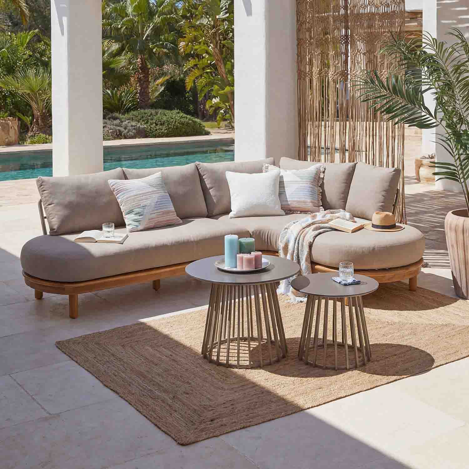Canapé d'angle beige avec base en bois et coussins en extérieur près de la piscine avec deux tables basses