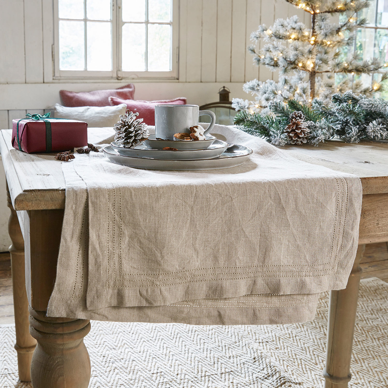 Tafelloper Brion Beige linnen tafelloper op houten tafel met kerstdecoratie en grijs servies
