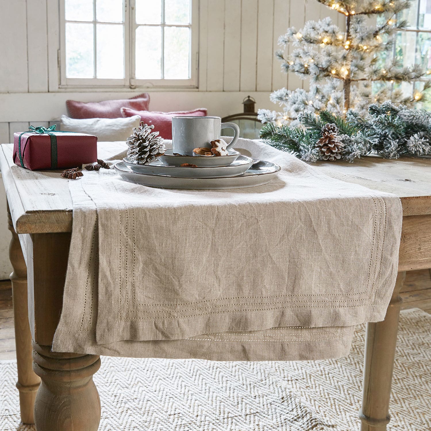 Chemin de table Brion Chemin de table en lin beige sur table en bois avec décorations de Noël et vaisselle grise
