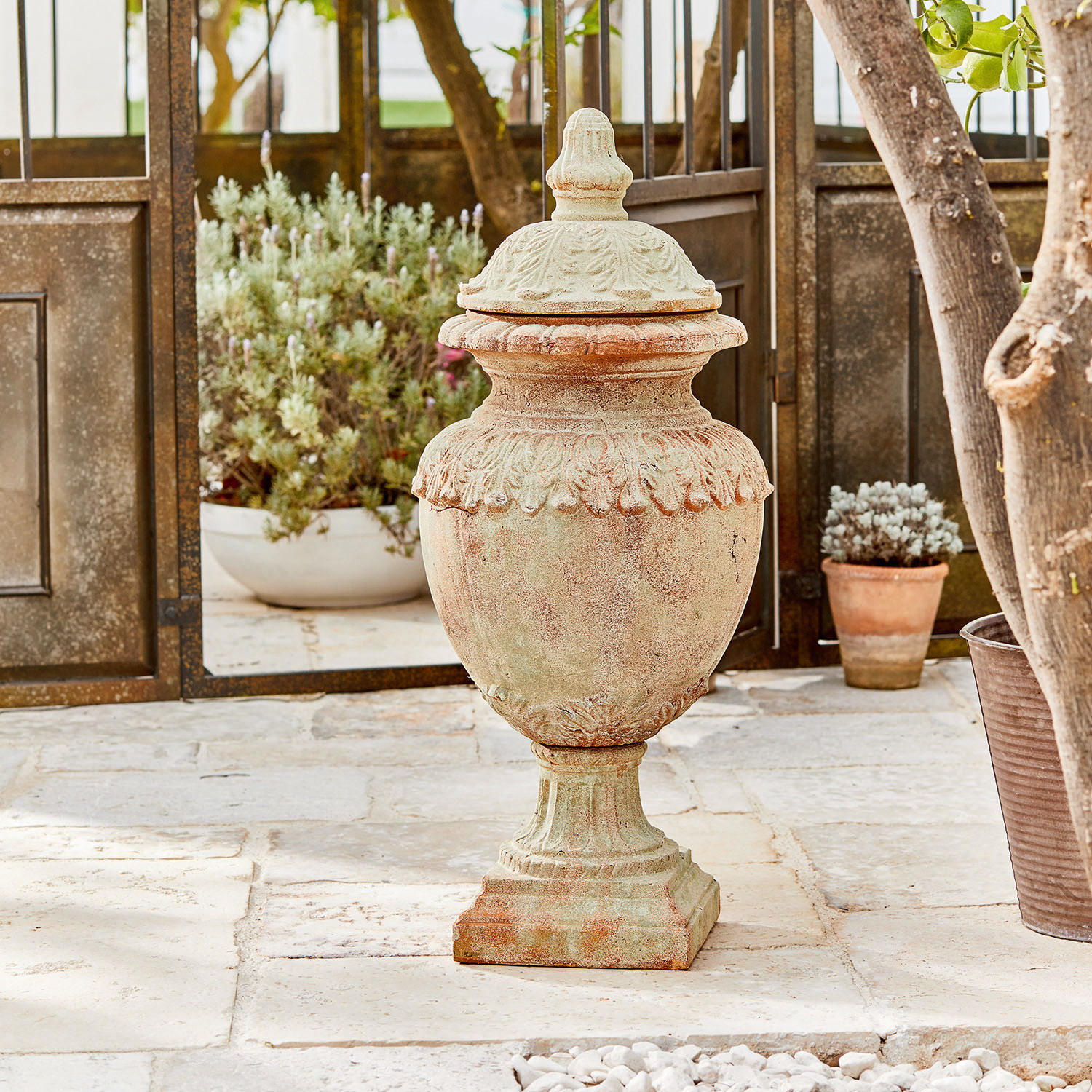 Objet décoratif Persephone Vase décoratif en terre cuite couleur naturelle sur sol en pierre avec plantes en arrière-plan