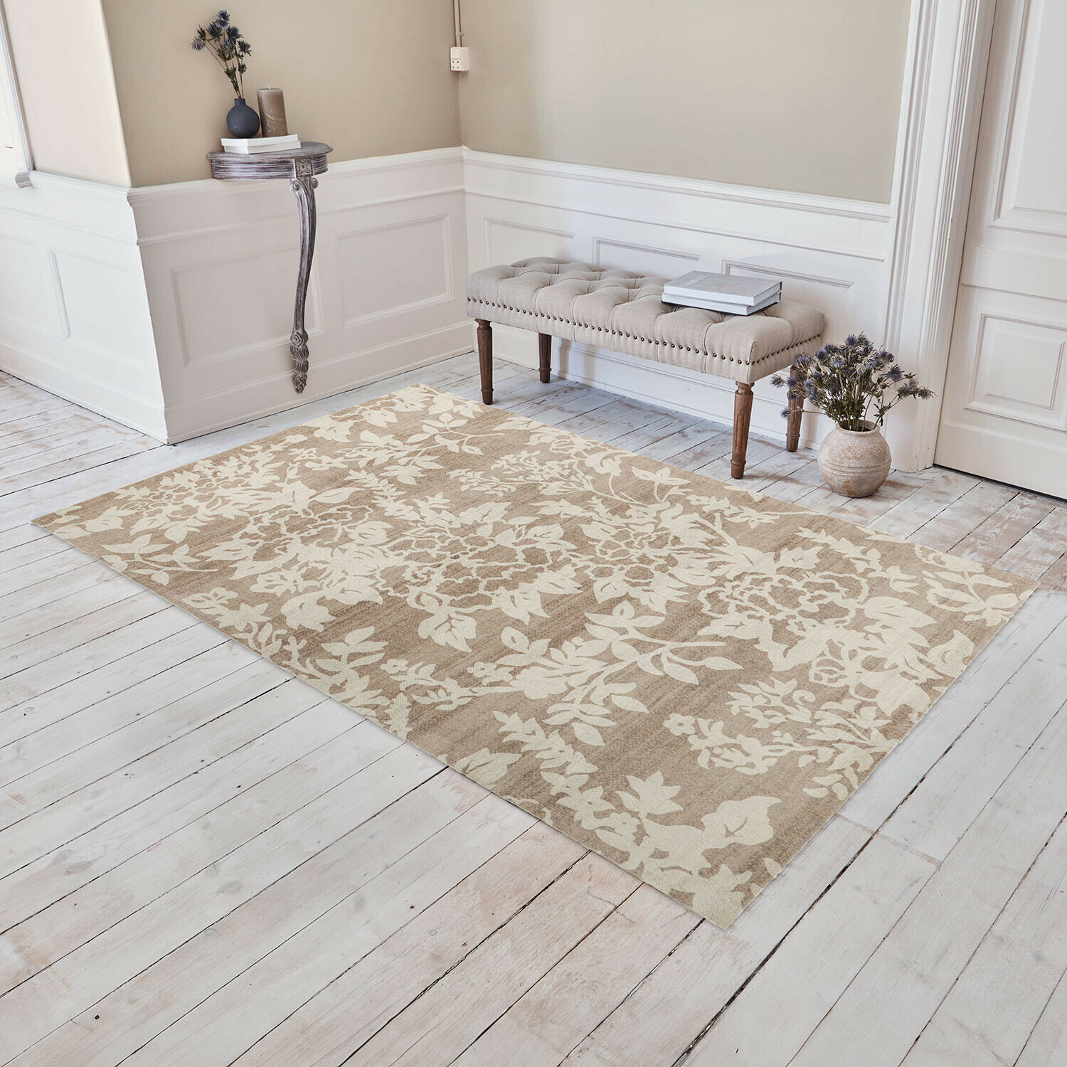 Vloerkleed Casamira Beige vloerkleed met bloemmotief op lichte houten vloer in elegante kamer met gestoffeerde bank