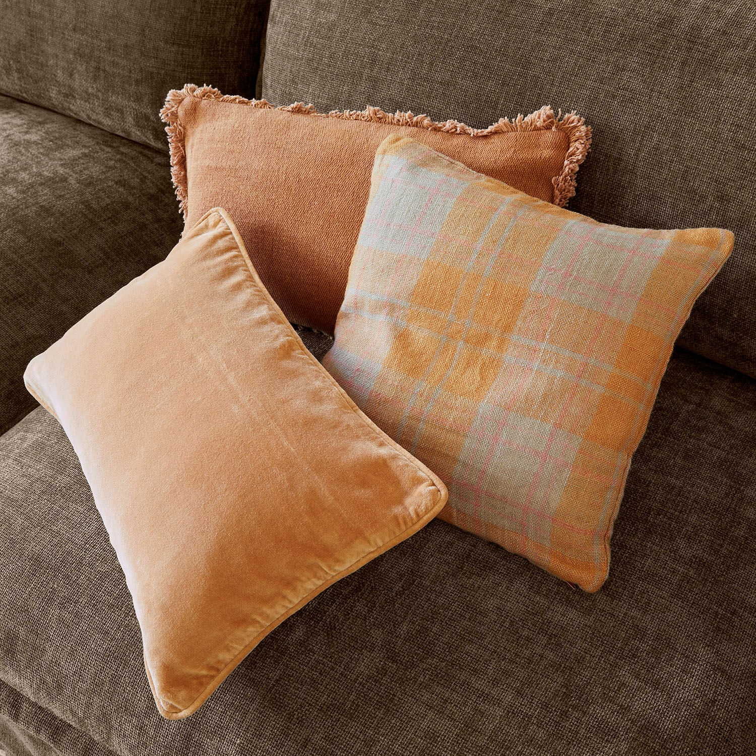 Kussenhoes set van 3 Léonille Drie decoratieve kussens in oranje tinten op een bruine bank voor een gezellige woonkamer