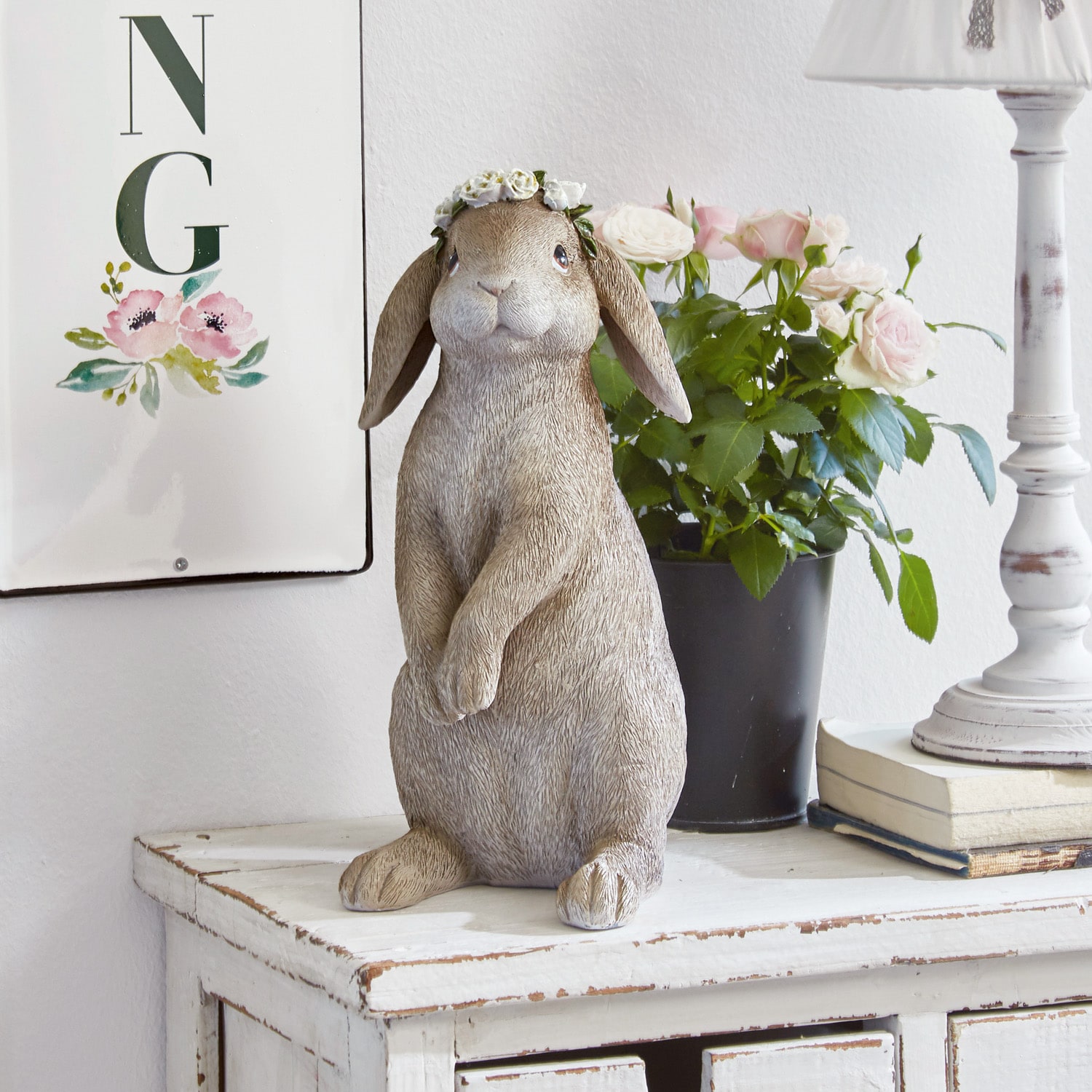 Decoratief konijnenbeeld in beige met bloemenkrans op een witte houten ladekast