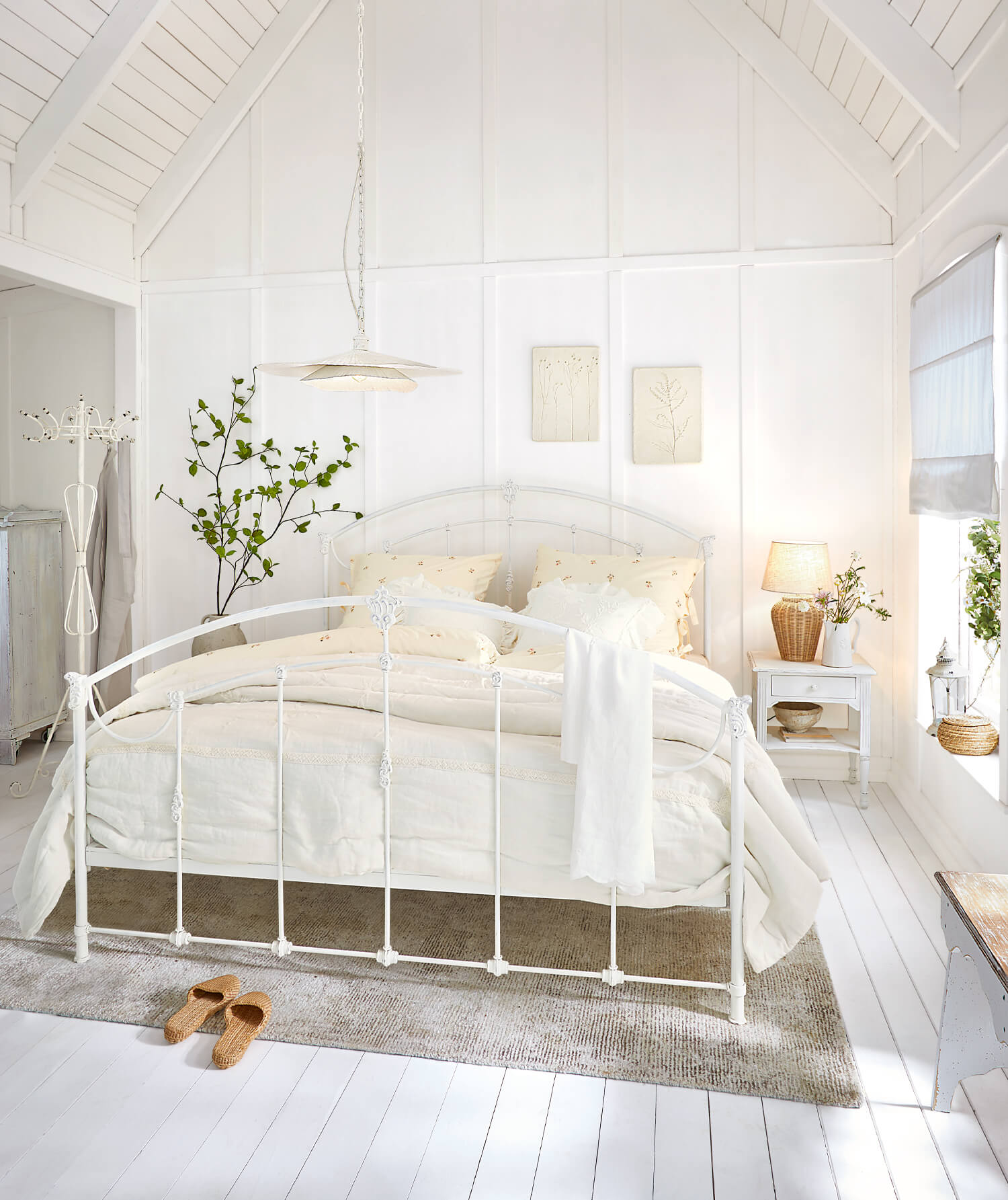 Cadre de lit en métal blanc dans une chambre lumineuse avec literie crème et tapis naturel