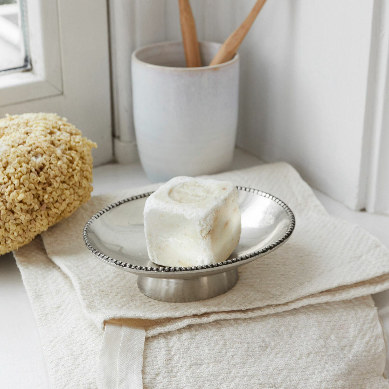 Porte-savon Michaelson Porte-savon en métal avec savon crème sur une serviette beige dans une salle de bain lumineuse