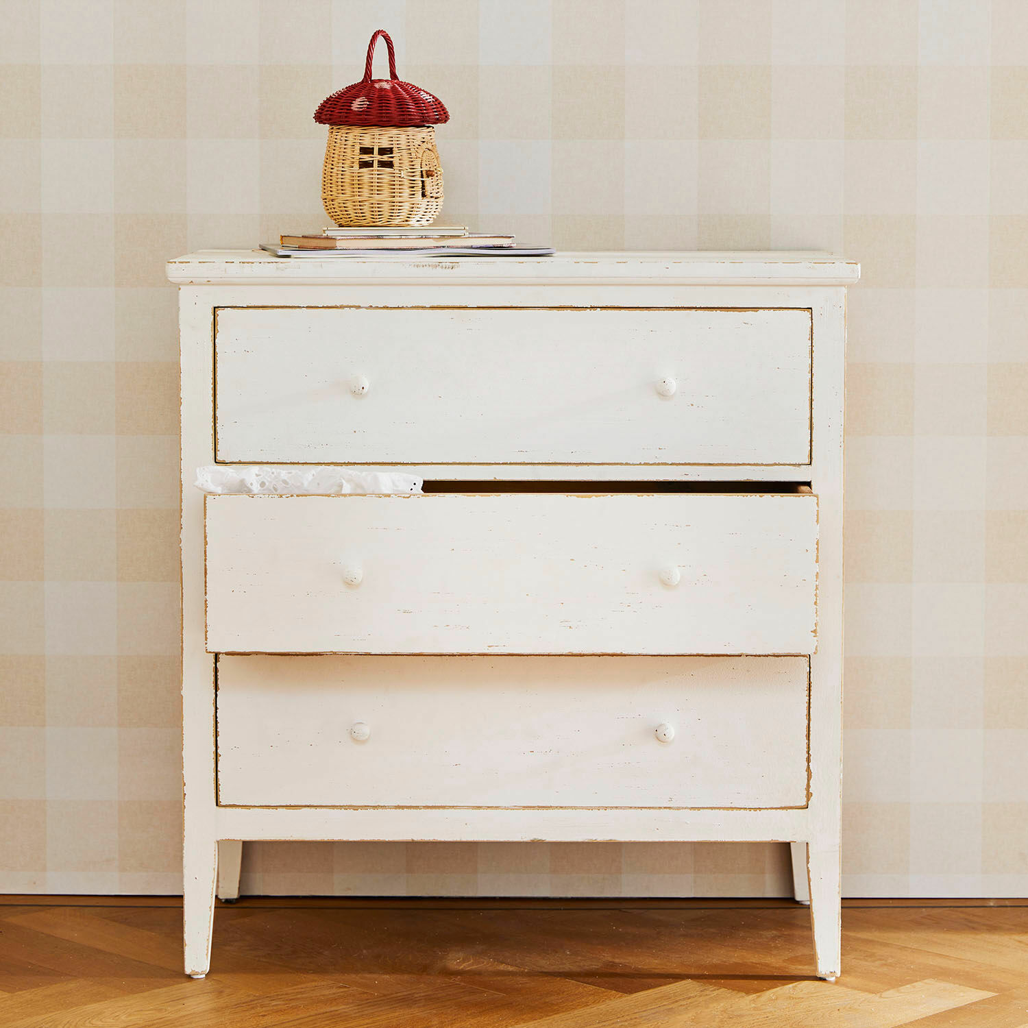 Ladekast Korelis Witte houten ladekast met drie laden en rood-beige rieten mand erop